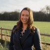 Woman wearing black stood smiling with a field in the background