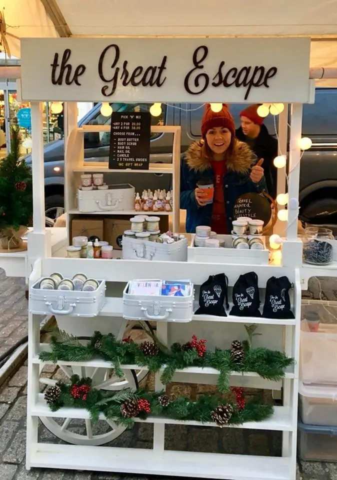 A woman behind a white cart at a market with her thumb up, demonstrating the importance of brand storytelling