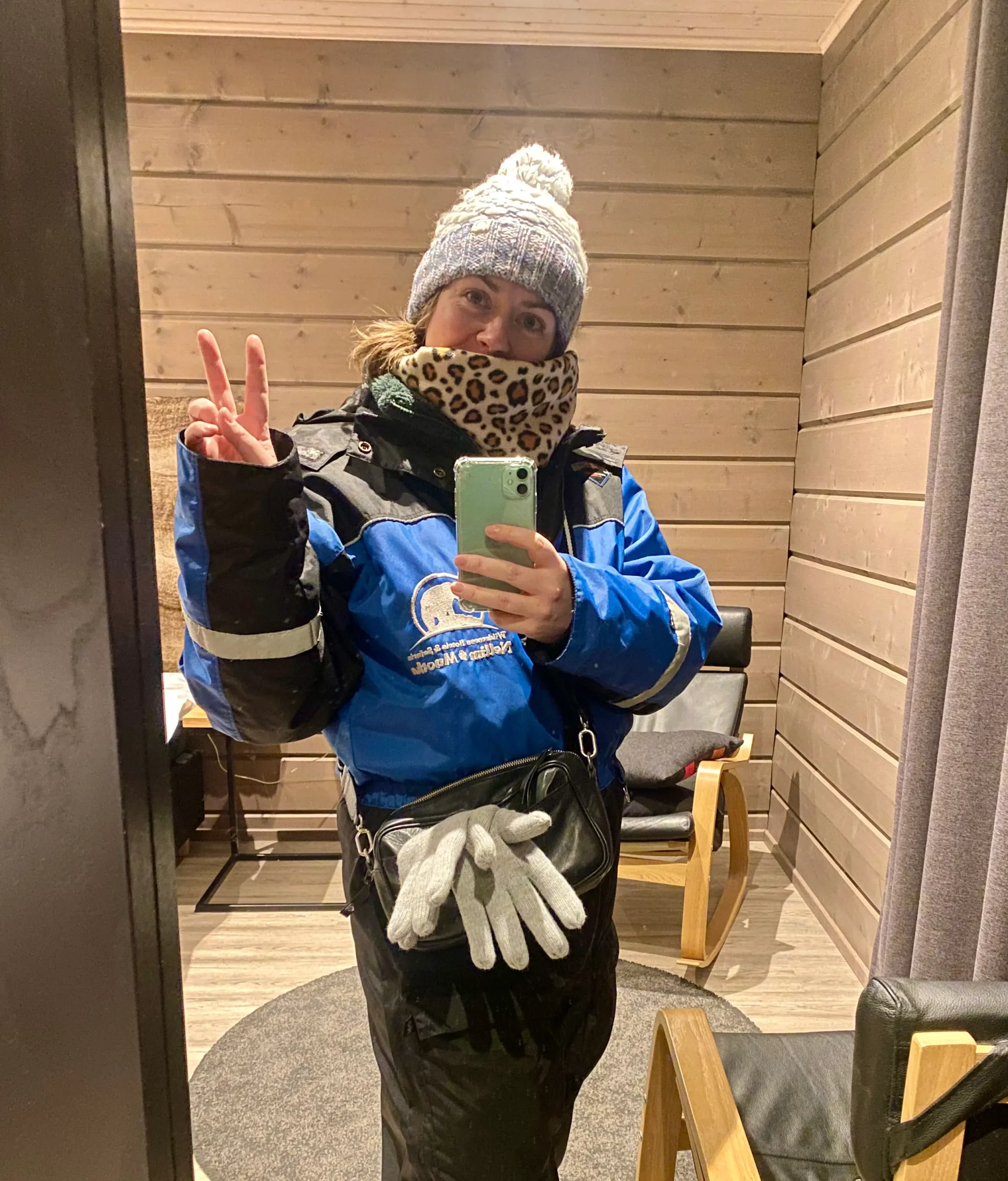 A woman in a blue and black snowsuit and winter gear demonstrating what to wear in Lapland in winter